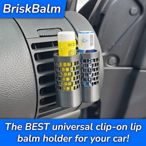 May include: A black clip-on lip balm holder with two compartments, each holding a lip balm. The holder is attached to a car vent. The text "BriskBalm" is at the top, and "The BEST universal clip-on lip balm holder for your car!" is at the bottom.
