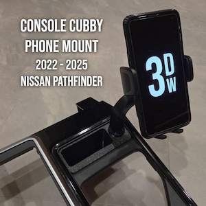 May include: Black console cubby phone mount for Nissan Pathfinder models from 2022 to 2025. The mount holds a smartphone with the text "3DW" displayed on the screen. The console has a cubby hole and a silver trim.