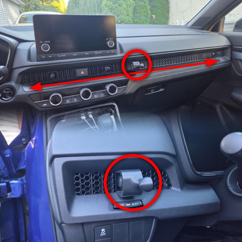 May include: A black magnetic phone mount attached to the honeycomb-patterned dashboard air vent of a vehicle. The mount features a circular ball joint head and is positioned horizontally across the passenger side dashboard trim area.