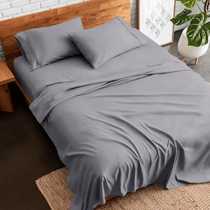 Può includere: Un letto grigio con un copripiumino grigio e due cuscini grigi. Il letto è fatto con un lenzuolo con angoli e un lenzuolo piatto. Il letto è su una struttura in legno.