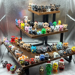 May include: A tiered display stand holds a collection of colorful animal figurines. The figurines include dogs, cats, and other creatures, each with unique features. The display stand is made of wood and metal, creating a charming and whimsical aesthetic.
