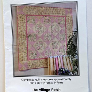 May include: A floral quilt with pink and cream colors, measuring 58 inches by 58 inches. The quilt has a pink border and a repeating pattern of pink and cream squares. The text "PRETTY CHINTZY" is at the top.