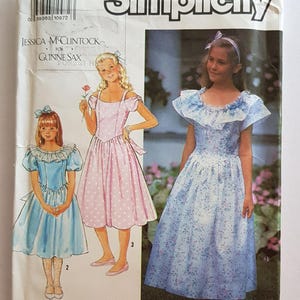 Puede incluir: Patrón de costura Simplicity con ilustraciones de niñas con vestidos. El patrón incluye diseños para varios vestidos, incluyendo un vestido rosa con lunares y un vestido floral azul. El patrón es de talla A (7-14).