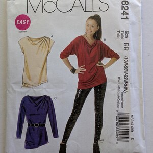 May include: Sewing pattern for a women's top with a cowl neck. The pattern includes three different styles: a short-sleeved top, a long-sleeved top, and a long-sleeved top with a belt. The pattern is for sizes 18W-20W-22W-24W. The pattern is from McCall's and is labeled "Easy".