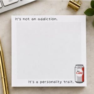 May include: A square white notepad with a light gray center area. The top text reads It's not an addiction. The bottom text reads It's a personality trait. A small illustration of a silver and red Diet Coke soda can is positioned in the bottom right corner.