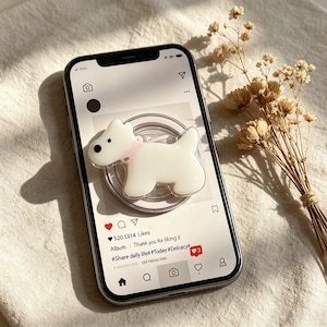 May include: A white dog-shaped phone grip with a pink collar attached to the back of a smartphone. The screen displays a social media interface with the text: 520.1314 Likes, Album. Thank you for liking it, #Share daily life #Today #Delicacy.
