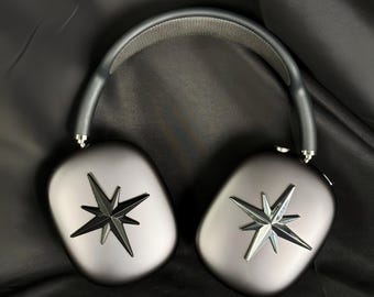 Può includere: Un paio di cuffie over-ear grigie con un'archetto nero. Ogni padiglione ha un design a forma di stella argentata.