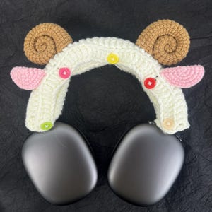 Peut inclure: Bandeau en crochet blanc avec des oreilles brunes et roses et des boutons color&eacute;s. Le bandeau est con&ccedil;u pour s'adapter sur des &eacute;couteurs.
