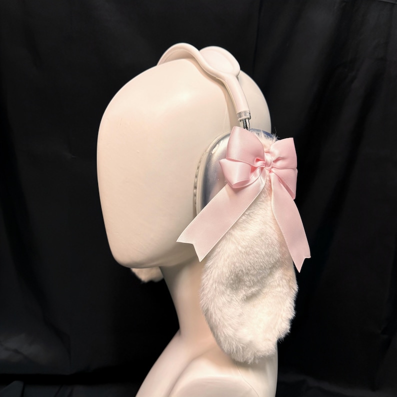 May include: White headphones with a fluffy white earmuff and a pink bow on one side.