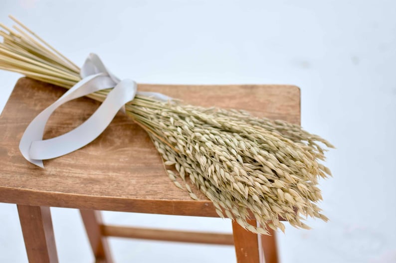 Dried oat bundle on wood stool.