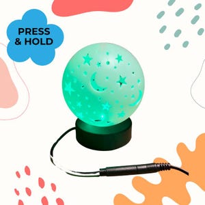 May include: A spherical lamp emitting a green glow, featuring cutouts of stars and crescent moons. The sphere rests on a black cylindrical base connected to a black power cord. A blue cloud-shaped graphic displays the text PRESS & HOLD.