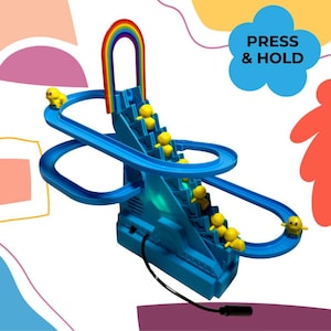 以下が含まれることがあります： 青いおもちゃのアヒルのスライドで、虹のアーチと黄色いアヒルの置物があります。おもちゃにはアヒルが滑り降りるためのトラックがあり、「PRESS & HOLD」と書かれたボタンがあります。このおもちゃは子供向けに設計されています。