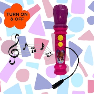 May include: A pink toy microphone with a purple top and a black cord. The microphone has two yellow buttons and a picture of two characters. The words "TURN ON & OFF" are in an orange flower-shaped bubble.