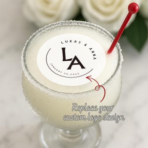 Może przedstawiać: Koktajl margarita w kieliszku z oszronionym brzegiem. Na wierzchu znajduje się biały, okrągły, jadalny obraz z napisem "LUKAS & ANNA" i "LA". W napoju znajduje się czerwony mieszadełko. Na jadalnym obrazie znajduje się również napis "JANUARY 20, 2025".