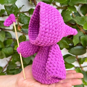 May include: A purple crocheted hooded doll holding a wooden stick with a pink heart-shaped top.