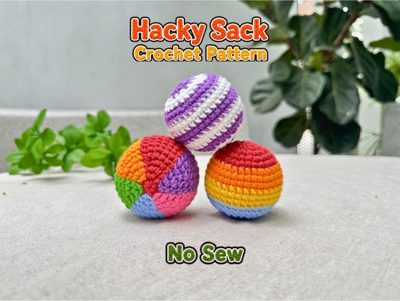 Colorful crochet hacky sack balls pattern display featuring three handmade amigurumi juggling balls in bright rainbow and striped designs, stacked on a light fabric surface with blurred green plants in the background. Includes no-sew crochet pattern text overlay. Soft chenille or plush yarn crochet hacky sacks with detailed stitch texture, perfect for juggling, fidget toys, beginner crochet projects, handmade gifts, and amigurumi pattern inspiration.