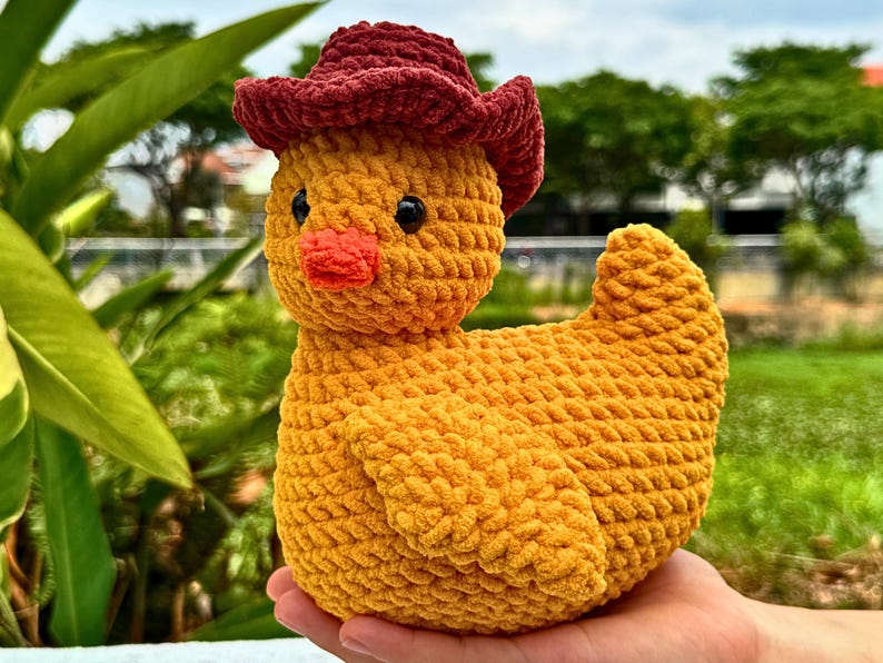 Pu&ograve; includere: Un'anatra all'uncinetto gialla fatta a mano con un cappello da cowboy bordeaux. L'anatra ha un becco arancione brillante e occhi neri. Il peluche &egrave; morbido e strutturato, perfetto per la cameretta di un bambino o come oggetto decorativo.
