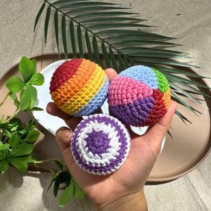 Crochet hacky sack pattern bundle showing 3 rainbow amigurumi balls - rainbow swirl, patchwork, and purple spiral designs