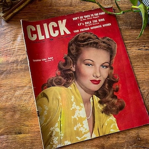 May include: Vintage "CLICK" magazine from December 1944, featuring a portrait of Veronica Lake on the cover. The magazine has a red background with headlines and text. The cover also includes the text "Veronica Lake: Rebel".