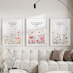 Könnte beinhalten: Drei gerahmte Drucke mit Aquarell-Blumenmotiven und inspirierenden Bibelversen. Die Verse lauten: "Der Herr ist mein Hirte, mir wird nichts fehlen", "Ich kann alles durch Christus, der mich stärkt", und "Wir lieben, weil er uns zuerst geliebt hat".