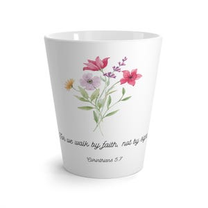 Op de afbeelding: Witte keramische mok met een aquarel bloemenontwerp en de quote "Want wij wandelen door geloof, niet door zien" met de schriftuurverwijzing "Korinthe 5:7".
