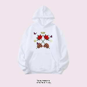 Puede incluir: Sudadera con capucha blanca con bolsillo delantero. El frente presenta un gr&aacute;fico de dos manos sosteniendo rosas rojas, con el texto "Catch Love" arriba. Mariposas moradas y detalles verdes completan el dise&ntilde;o.
