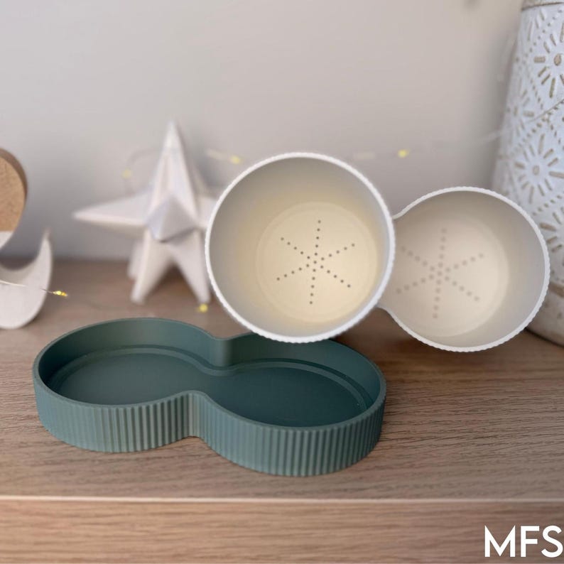 a wooden shelf with various decorative items, including a white star-shaped ornament, a green bowl-shaped container, and a white vase with a floral pattern.