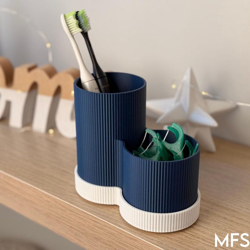 A blue and white toothbrush holder with a toothbrush and toothpaste inside, placed on a wooden shelf.