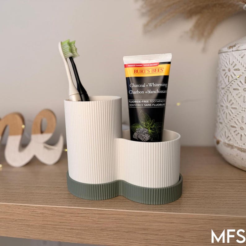A white toothbrush holder with a tube of toothpaste inside, placed on a wooden surface.