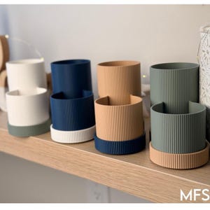 A row of colorful planters on a wooden shelf, featuring various shades of blue, brown, and green.