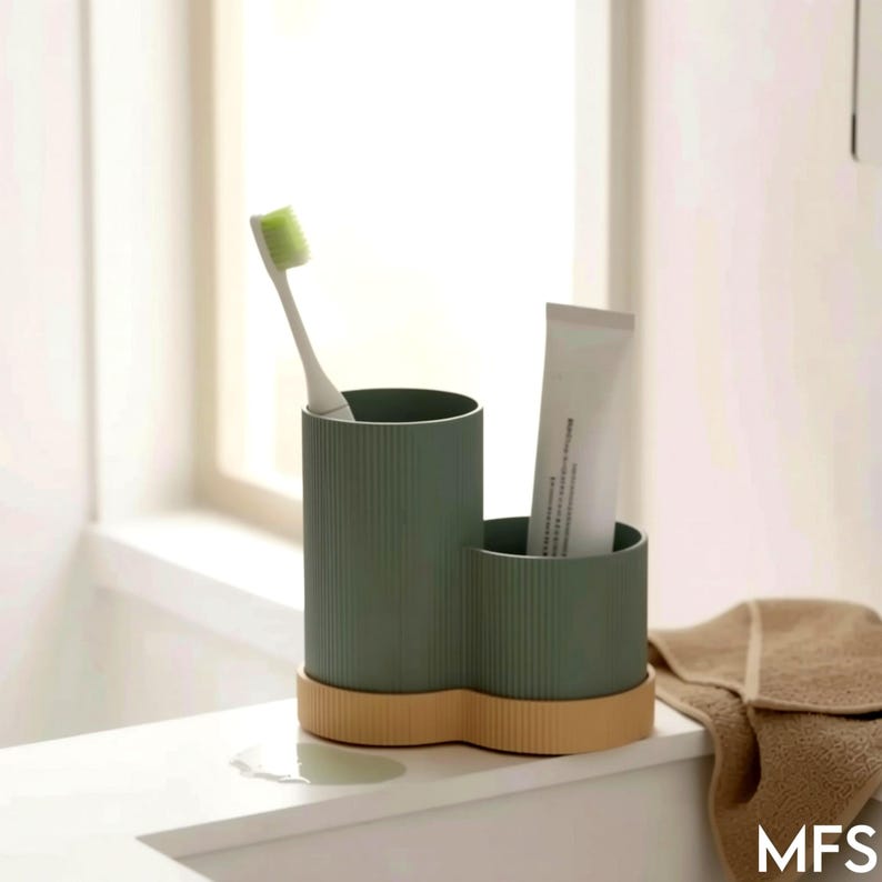 A person in a beige robe is reaching for a toothbrush in a toothbrush holder on a bathroom counter.