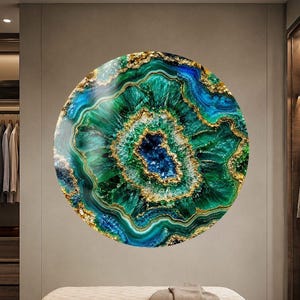 Puede incluir: Una gran pieza de arte mural circular con un patrón inspirado en la ágata, con anillos concéntricos de verde esmeralda profundo, azul turquesa y azul real, acentuados por vetas doradas brillantes que irradian desde un centro cristalino azul.