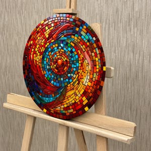 May include: A circular mosaic wall art piece with a swirling pattern of red, orange, yellow, blue, and green glass tiles. The center of the mosaic features a smaller circle of red tiles.