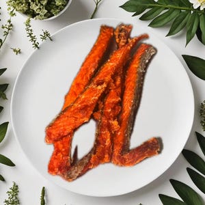 May include: A close-up of four orange salmon skin strips on a white plate. The salmon skin is crispy and has a light brown color.