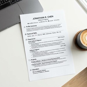 May include: A printed resume for Jonathan R. Chen, a software engineer, featuring sections for profile summary, technical skills, experience, projects, and education, placed next to a laptop and a dark mug filled with coffee featuring latte art.