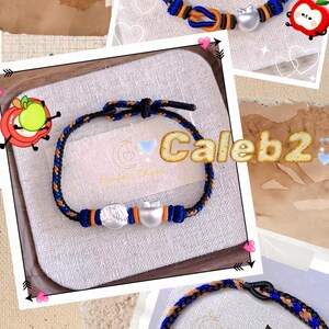 May include: Three handmade bracelets with blue, orange, and black braided cords. Each bracelet features a silver charm and a knot closure. The bracelets are displayed on a neutral background with decorative elements.
