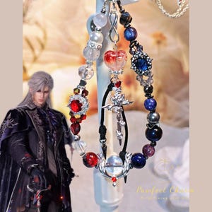 May include: A collection of beaded charms with various designs. The charms feature red, blue, and clear beads, along with silver-colored metal accents. Some charms have a cross or heart shape. The background is a soft, neutral color.