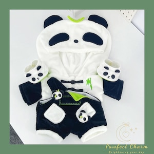 Könnte beinhalten: Ein Panda-Themen-Haustier-Outfit in Weiß, Schwarz und Grün. Das Outfit umfasst ein Kapuzenoberteil mit Panda-Gesichtsdetails, Shorts und passende Pfotenabdeckungen. Das Outfit hat ein Bambusdesign und einen Knebelverschluss.