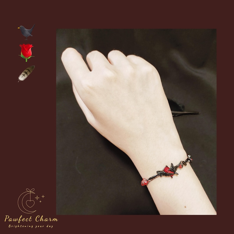 Op de afbeelding: Een zwarte armband van touw met rode hartcharms. De armband zit om een pols.