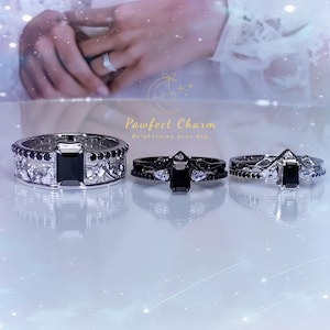 May include: Three silver rings with black rectangular and round gemstones. The rings have intricate designs, with one featuring a crown-like shape. The brand name "Pawfect Charm" is visible in the image.