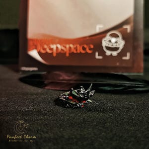 May include: Black ring with a red heart-shaped stone and intricate details. The ring is set against a dark background.