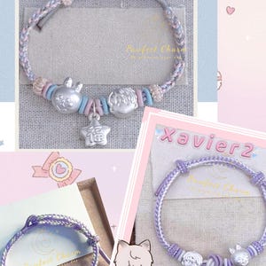 May include: Three bracelets with braided cords in shades of purple, blue, and gray. Each bracelet features silver charms, including a bunny, a boy, and a star with Chinese characters. The text "Xavier" is visible on the packaging.