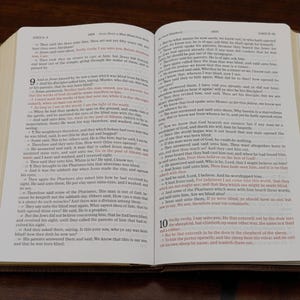 May include: Open Bible with text from the Gospel of John. The pages are yellowed with age, and the text is in black ink. The Bible is open to a passage about Jesus healing a blind man.