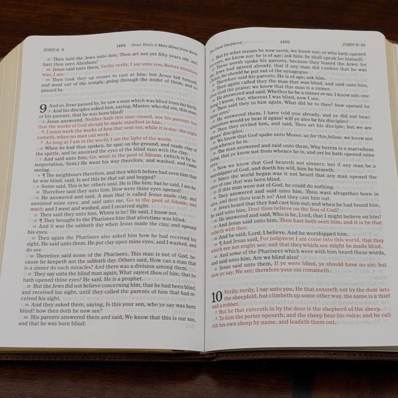 May include: Open Bible with text from the Gospel of John. The pages are yellowed with age, and the text is in black ink. The Bible is open to a passage about Jesus healing a blind man.