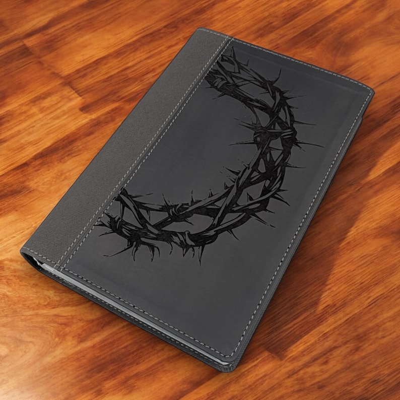 Op de afbeelding: Een grijs lederen gebonden dagboek met een zwart, reli&euml;f ontwerp van een doornenkroon.