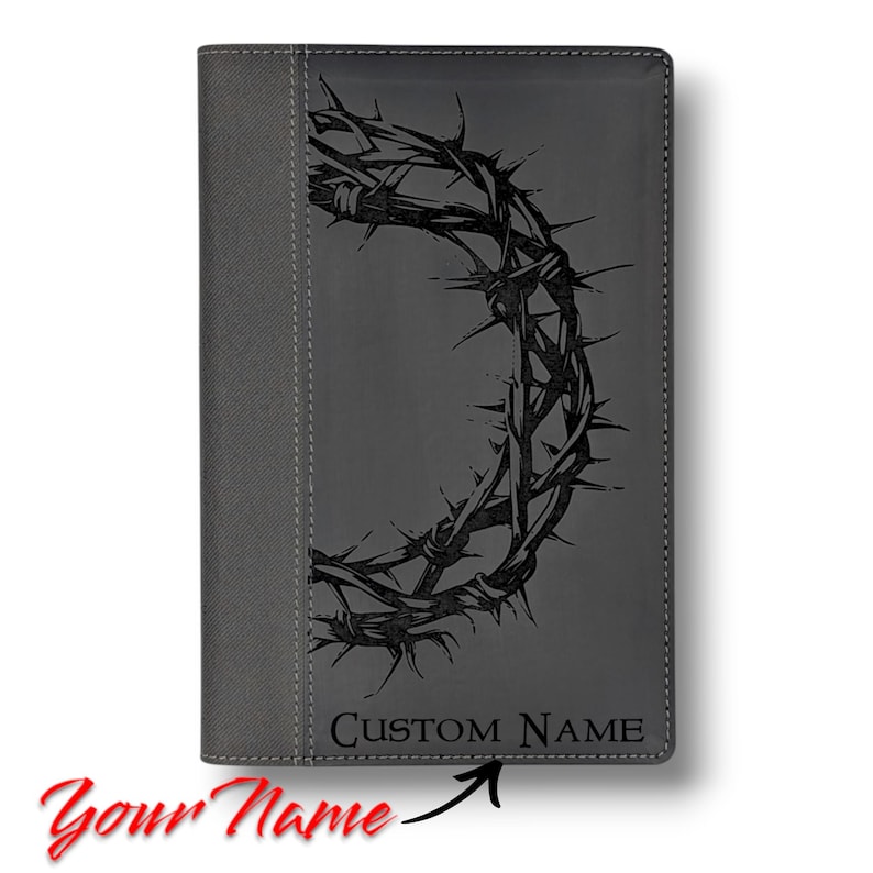 Op de afbeelding: Grijs lederen dagboek met een zwart doornenkroonontwerp en de tekst "CUSTOM NAME" op de voorzijde.