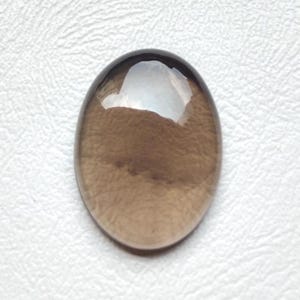 May include: An oval-shaped, translucent gemstone with a smooth, polished surface. The stone displays a deep, earthy brown colour with subtle variations in tone throughout its body, and a bright white light reflection visible on its upper portion.