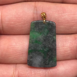 May include: A rectangular jade pendant with a green and black mottled pattern, set in a gold bail.