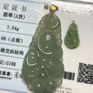 May include: A jade pendant with a gold bail, featuring a light green, organic shape with carved details. A smaller, similar pendant is also visible. The background includes a certificate with Chinese characters and the weight of the larger pendant, 7.54g.