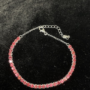 May include: A silver bracelet with a pink crystal tennis chain design.